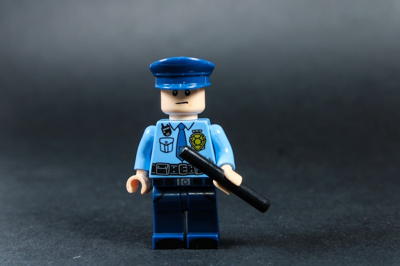 Lego police officer holding a baton against dark background