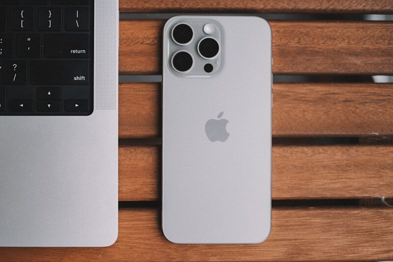 An iPhone and a laptop on a wooden table